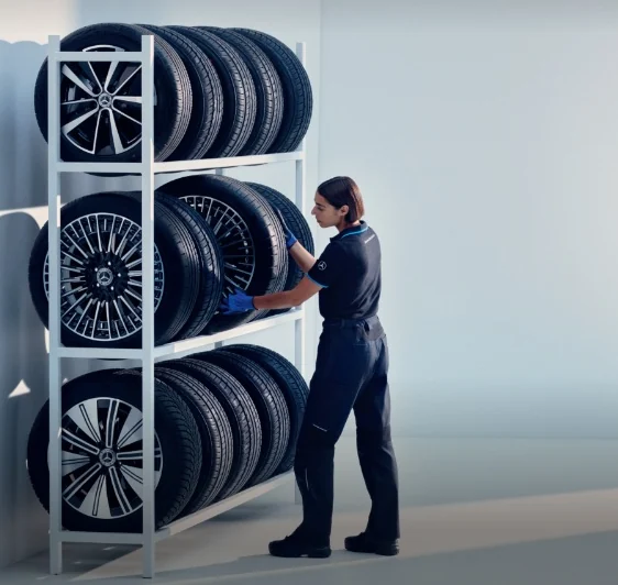 Consilier de service Mercedes-Benz lângă un raft cu roți complete de iarnă originale